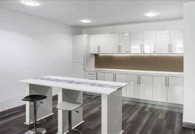 Modern white kitchen breakout area with a central island and breakfast bar stools.