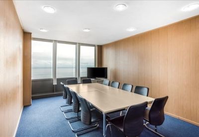 Professional boardroom with a long table, black chairs, and wood-paneled walls.