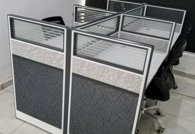 Modern four-person workstation pod with grey patterned privacy screens.