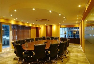 Elegant wood-paneled boardroom with a large oval table and warm recessed lighting.