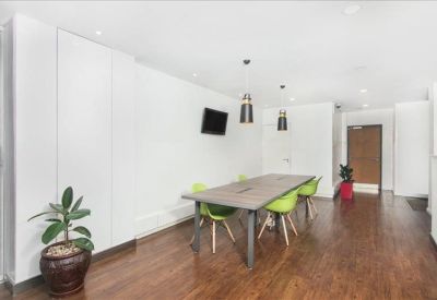 Spacious communal dining area featuring a long wooden table and vibrant green chairs.