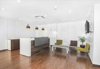 Modern reception area with a wood-panelled desk, stylish seating, and warm wooden flooring.