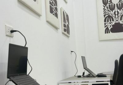 Modern workstation featuring a laptop on a stand, keyboard, and minimalist floral wall decor.