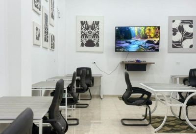 Collaborative office space with individual desks and comfortable swivel chairs.