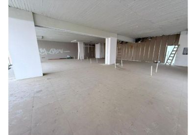 Large, unfinished commercial space featuring white support columns and raw ceiling detail.