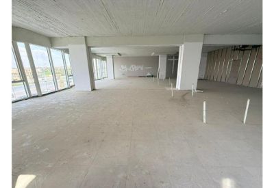 Interior view of an expansive office area showing structural pillars and wall framing under construction.
