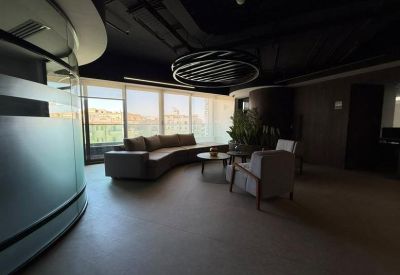 Lounge area with a curved grey sofa and floor-to-ceiling windows.