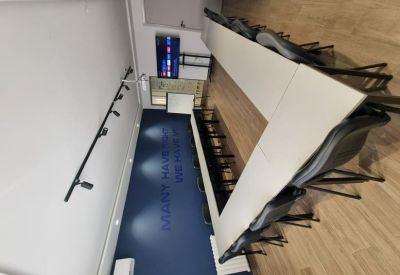 Overhead view of a long white boardroom table with grey chairs and a blue wall.