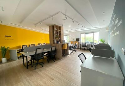 Bright coworking space with a yellow feature wall, wooden flooring, and shared desks.