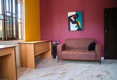 Small seating area with a brown sofa, colorful abstract art, and a wooden desk.