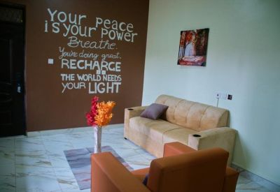 Lounge area with a tan sofa, orange armchair, and floral arrangement.