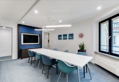 Modern conference room featuring a blue accent wall, teal chairs, and sleek lighting.