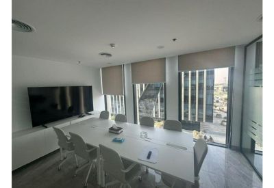 Professional meeting room with a large white conference table and integrated wall-mounted TV.