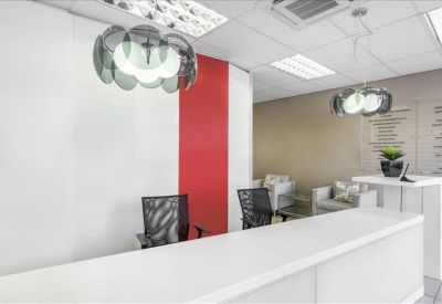 Reception area with a long white front desk and vibrant red feature wall.