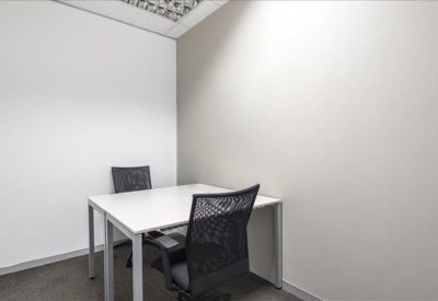 Small two-person internal office with white desks and black mesh chairs.