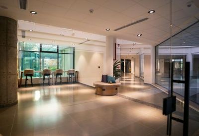 Spacious hall with marble floors, a seating bench, and a view into a glass-walled courtyard.