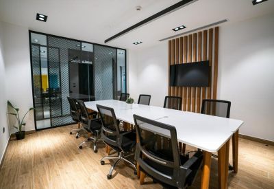 Modern conference room with a long white table, black mesh chairs, and a wood-slat feature wall.
