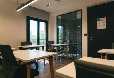 Bright workspace featuring several individual desks and ergonomic black chairs.