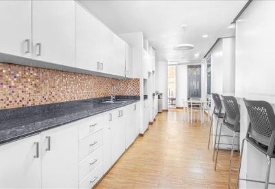 Spacious office kitchen with white cabinetry, dark granite counters, and breakfast bar seating.