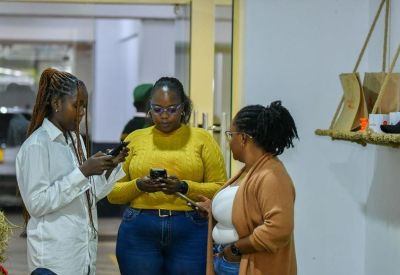 Three colleagues collaborating and using smartphones in a bright hallway.