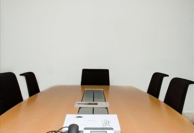 Boardroom with a long wooden table, black chairs, and a conference phone.