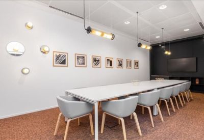 Meeting room with a long white table, gray chairs, and framed art on the wall.