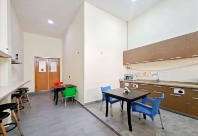 Shared kitchen and breakroom featuring a wood-toned cabinetry and colorful blue and green chairs.