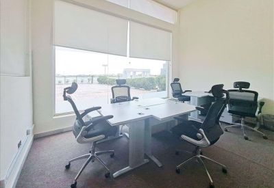 Four-person office suite with grey carpet, white desks, and large windows with blinds.