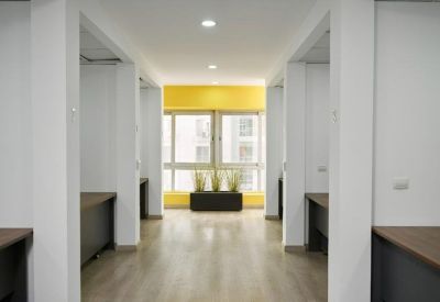 Bright open-plan office corridor with workstations and a yellow feature wall.