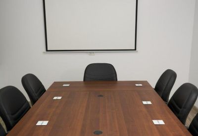 Professional boardroom with a large wooden table and projection screen.