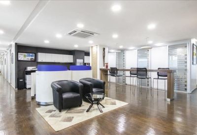 Spacious communal lounge with black armchairs and light wooden flooring.