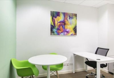 Small office with green chairs and colorful abstract art.
