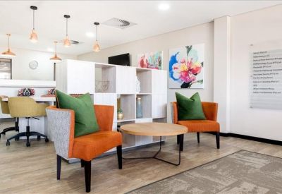 Colorful breakout area with orange armchairs, green cushions, and vibrant wall art.