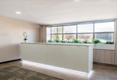 Clean, minimalist white reception desk with integrated lighting near large windows.