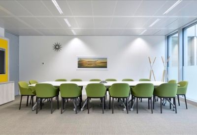 Spacious boardroom with light green chairs and a long white table.