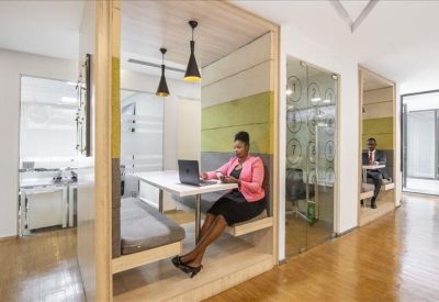 Modern wooden semi-private work booth with a person using a laptop.