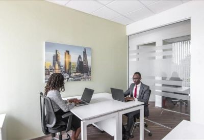 Private two-person office suite with white desks and glass partitions.