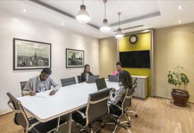Professional meeting room with a white table, black chairs, and framed artwork.