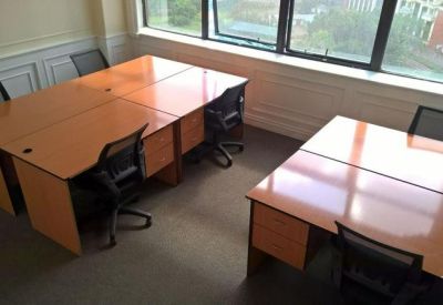 Private two-person office suite with wooden desks and black leather chairs.