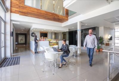 Lounge area with neutral sofas, a geometric patterned ceiling feature, and large windows.