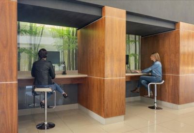 Private wood-paneled workstations with modern bar stools and a view of greenery.