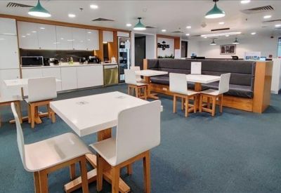 Bright office kitchen and break area with white cabinetry and dining tables.