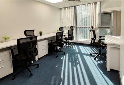 Private office suite with a long white desk and natural light from large windows.