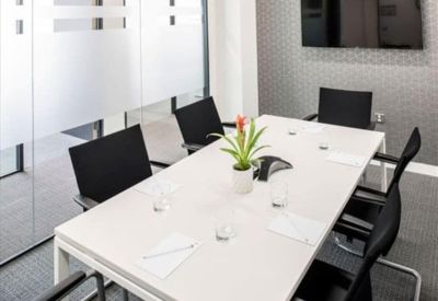 Professional meeting room featuring a white table, black chairs, and a wall-mounted TV.
