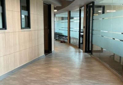 Modern corridor with wood-paneled walls and frosted glass office partitions.