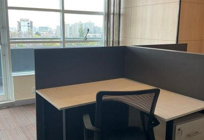 L-shaped cubicle desk with ergonomic chair and privacy screens.