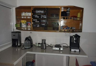 Coffee preparation area with various machines on a light countertop under wooden cabinets.