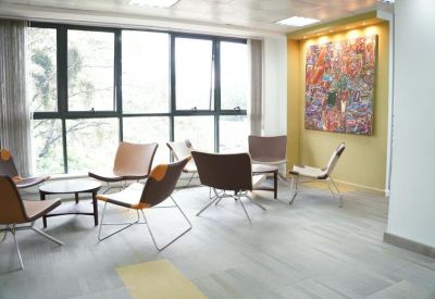 Sunlit lounge area with modern low-profile chairs, small coffee tables, and vibrant artwork.