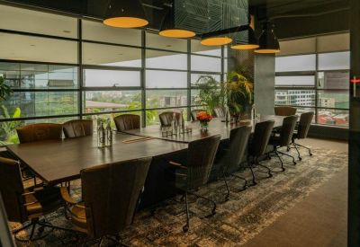 Professional boardroom with a long wooden table, leather chairs, and expansive window views.