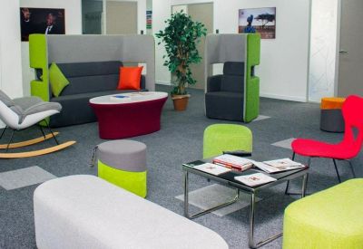 Vibrant communal lounge with colorful pod seating, a red coffee table, and a potted plant.